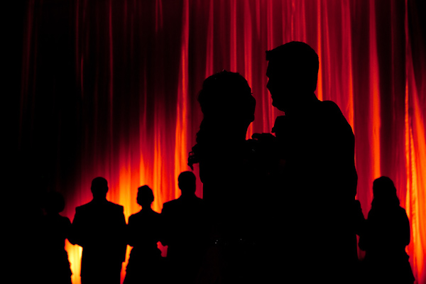 silhouette of bride and groom and the wedding party with a purple and orange lighting in the background - photo by Houston based wedding photographer Adam Nyholt 